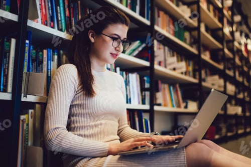 Preview: Female student with laptop doing homework in library