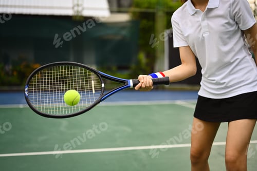 Preview: Cropped shot of sporty woman tennis player hitting ball with a racket during match.