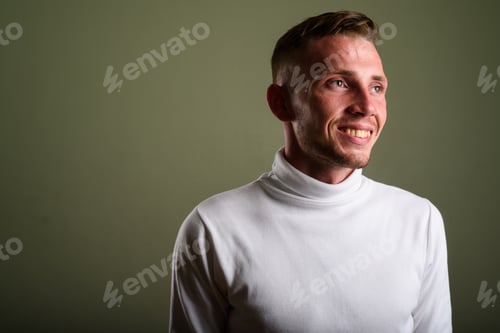 Preview: Young man wearing white turtleneck sweater against colored backg