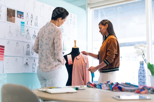 Preview: Diverse female fashion designers working together working on garment on dressmaker model