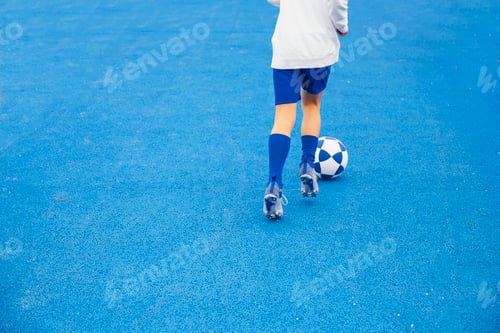 Preview: Little unrecognizable boy playing soccer of blue background