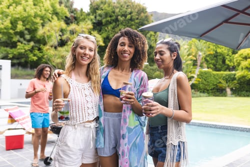 Preview: Three diverse female friends enjoy a poolside gathering, holding drinks and smiling warmly