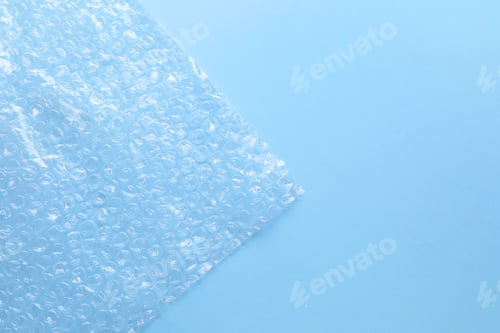 Preview: Transparent bubble wrap on light blue background, top view. Space for text