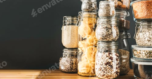 Preview: Banner with assortment of uncooked grains, cereals and pasta in glass jars on wooden table. Healthy