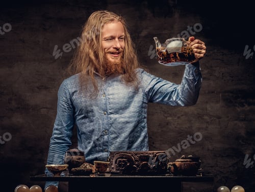 Preview: Bearded redhead male in a blue shirt preparing tea