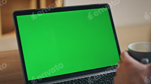 Preview: Businessman video calling greenscreen laptop holding coffee cup close up.