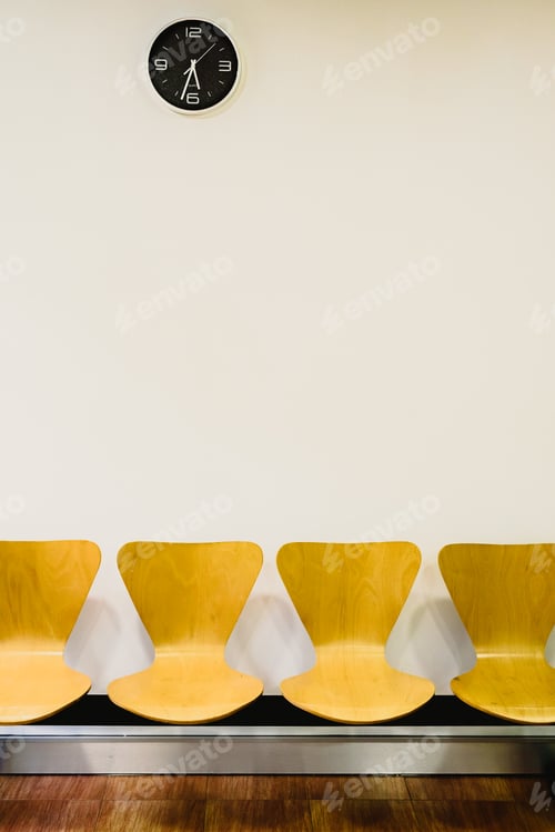Preview: Waiting room with empty wooden chairs and wall clock, waiting concept.