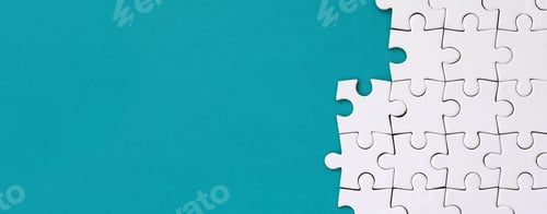 Preview: Fragment of a folded white jigsaw puzzle on the background of a blue plastic surface