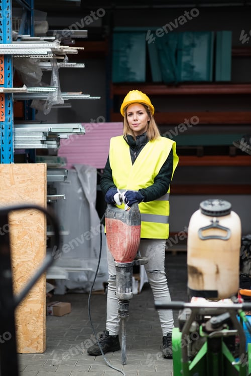Preview: Woman worker with jackhammer in an industrial area.
