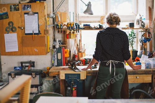 Preview: Rear view of young craftswoman at workbench in pipe organ workshop