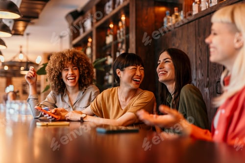 Preview: Cheerful female friends laughing and enjoying time together in cafe