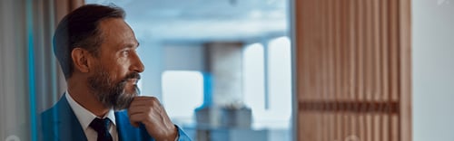 Preview: Adult bearded businessman looking away thoughtfully in office