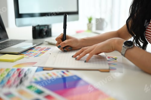 Preview: Young creative woman choosing color samples for design project at graphic studio.