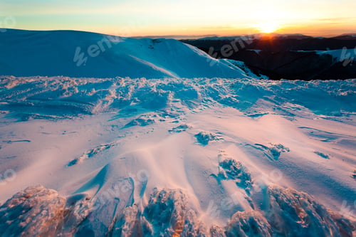 Preview: Sunset over mountains covered with snow in winter clear day