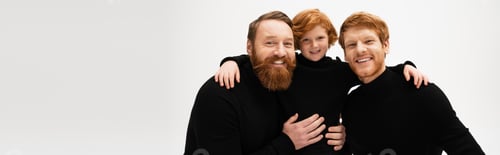Preview: happy bearded men embracing red haired boy and smiling at camera isolated on grey, banner