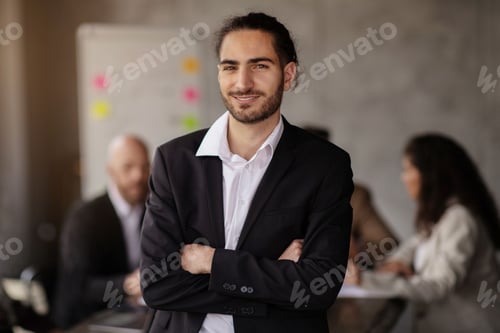 Preview: Successful young businessman posing with confidence amidst modern office interior