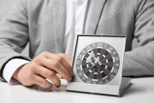 Preview: Man with darts at table. Business trainer concept