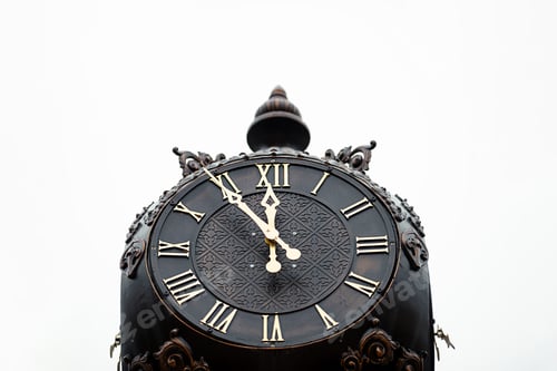 Preview: Horizontal photo of a street metal brown clock with Roman numerals close-up.
