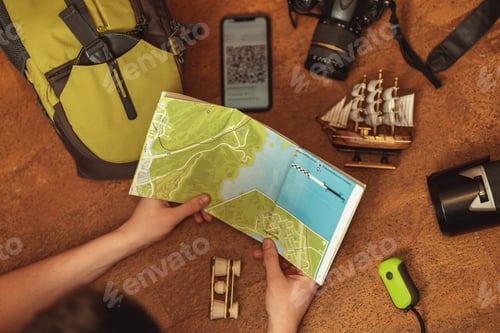Preview: Travel flat lay. a young man examines a map before going on a trip