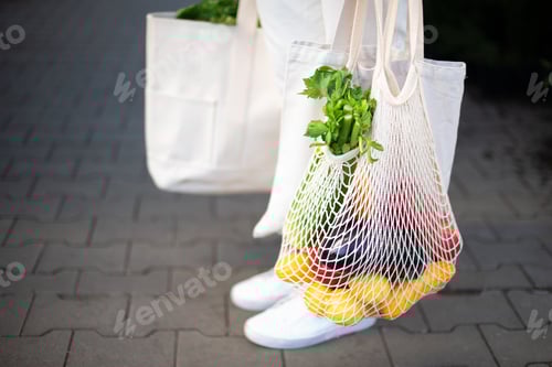 Preview: Girl holding mesh shopping bag and cotton shopper with vegetables without plastic bags at farmers