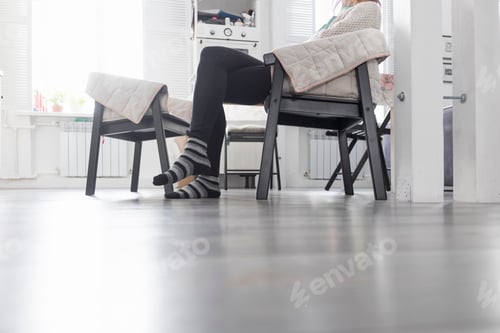 Preview: Woman sitting in chair in kitchen, low section