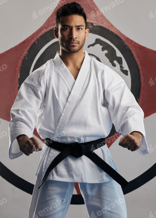 Preview: Cropped portrait of a handsome young martial artist practicing karate in his dojo