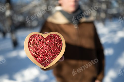 Preview: Close up heart shaped gift in man hands outdoors