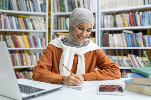 Preview: Muslim woman studying with books and laptop in library