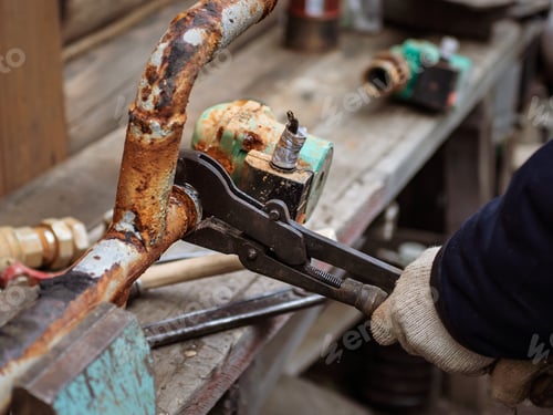 Preview: A man unscrews the crane from the rusty pipe with a wrench