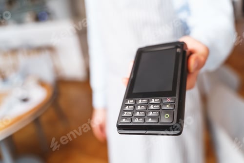 Preview: Young man holding terminal for contactless payment