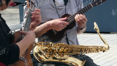 Preview: close up of musicians performing outdoors playing saxophone and ukulele