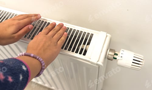 Preview: The child's hands warm their hands near the heating radiator. Saving gas in the heating season.