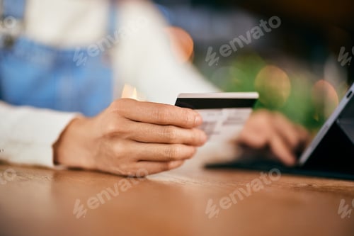 Preview: Close-up photo of a female holding and using a credit card, entering data into the tablet.