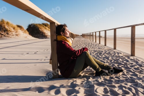 Preview: young woman with eyes closed relaxing at beach at sunset. Holidays and relaxation concept