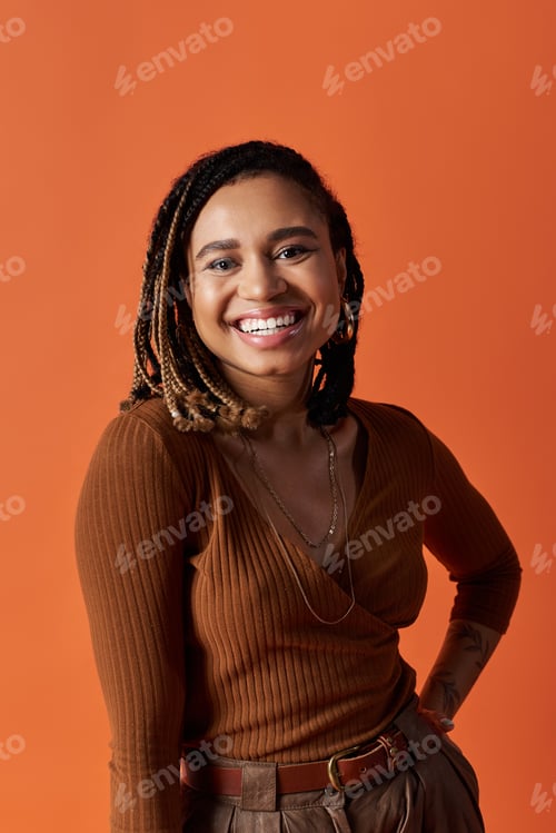 Preview: Stylish young African American woman with braids smiling in a vibrant studio setting