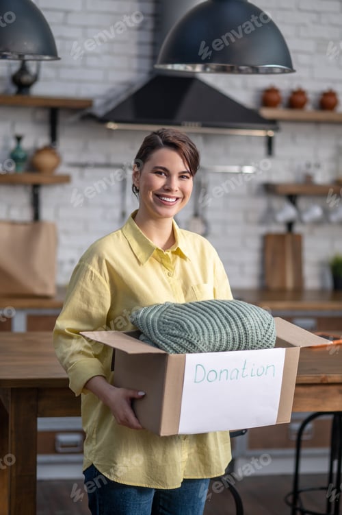 Preview: Volunteer holding a cardboard box filled with items of clothing
