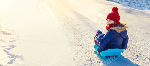 Preview: A child girl slides down a hill in the snow. Selective focus.