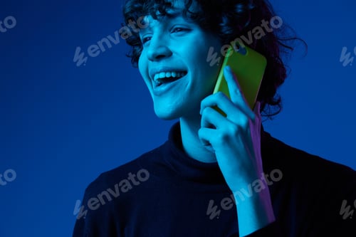 Preview: Man with phone in hand talking on smartphone smile, portrait dark blue background, neon light, style