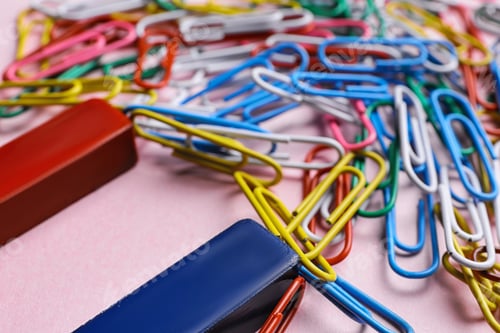 Preview: Red and blue horseshoe magnet attracting colorful paperclips on pink background, closeup