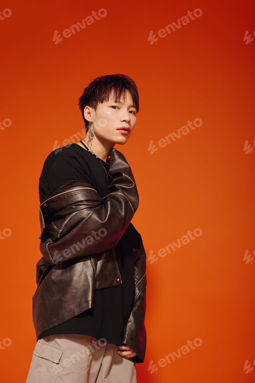 Preview: Stylish young man with urban flair poses confidently against vivid orange backdrop