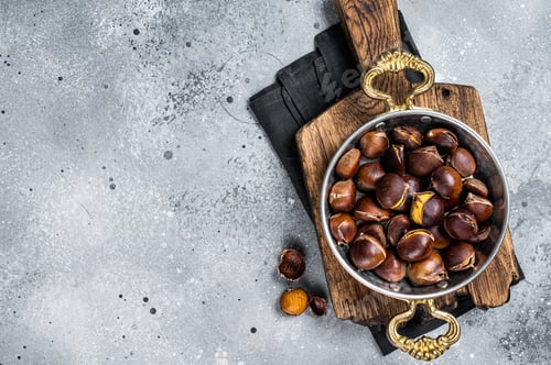 Preview: Cracked roasted chestnuts served in a skillet. Gray background. Top view. Copy space