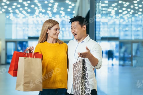 Preview: Young happy married couple shoppers man and woman in the supermarket are happy and laughing talking