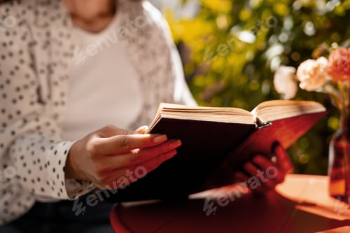 Vista previa: Woman enjoying reading a book in a peaceful garden setting