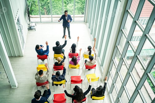 Preview: Raised up hands of large group in seminar class room to agree with speaker at conference seminar