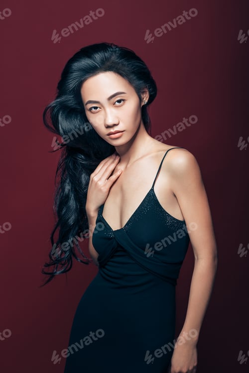 Preview: Beautiful asian woman in black dress posing in studio