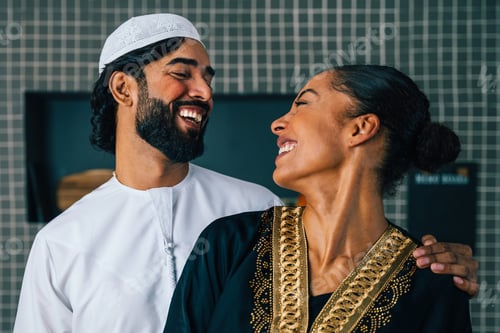 Preview: Happy beautiful young arab couple with emirati clothing together at home