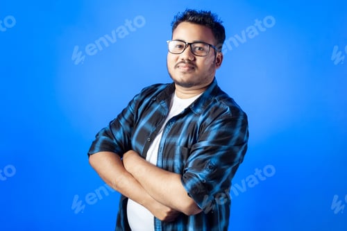 Preview: confident Happy Indian man standing, wearing glasses in blue bac
