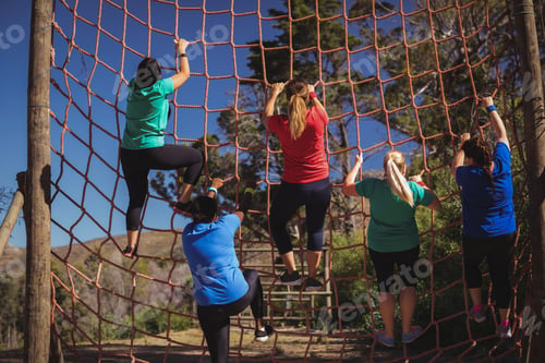 Preview: Group of fit woman climbing a net during obstacle course training