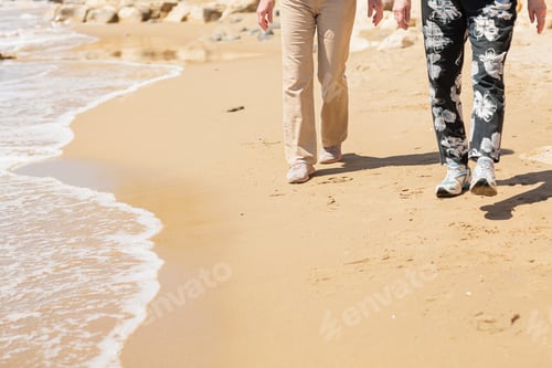 Preview: Two unrecognizable senior women walking along rocky seashore