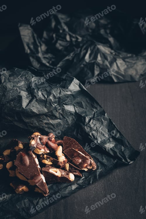 Preview: Pieces of chocolate with nuts on a crumpled gray paper